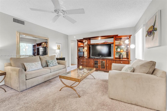 carpeted living room featuring ceiling fan and a textured ceiling