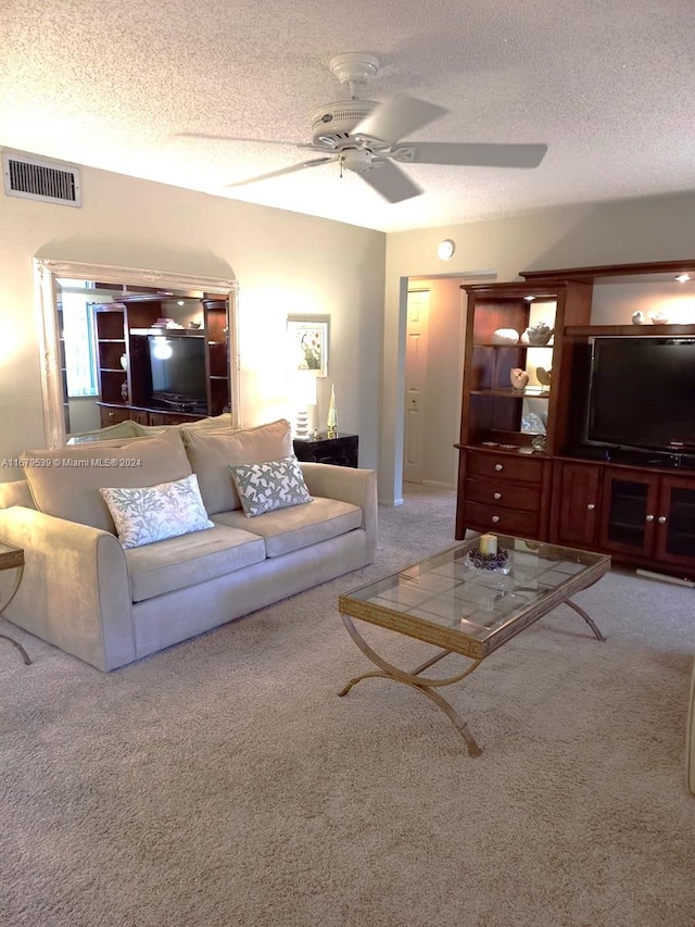 living room with ceiling fan, carpet floors, and a textured ceiling