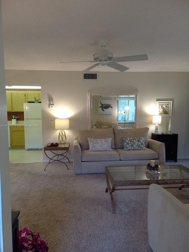 living room with a textured ceiling, light colored carpet, and ceiling fan