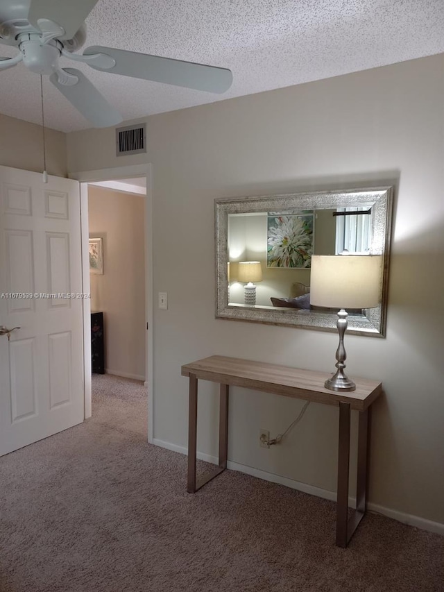 hall with carpet flooring and a textured ceiling