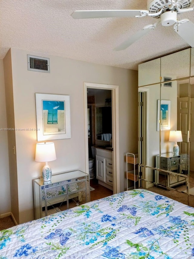 bedroom with ceiling fan, ensuite bathroom, and a textured ceiling