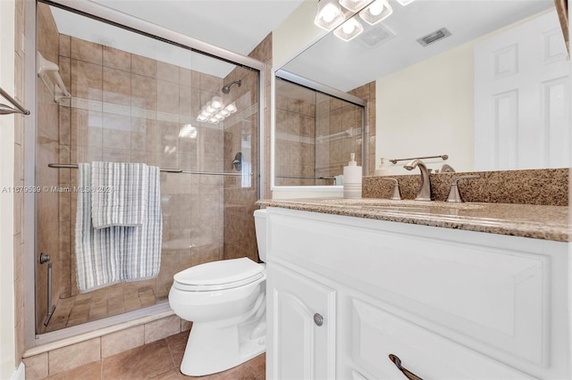 bathroom with tile patterned floors, a shower with door, vanity, and toilet