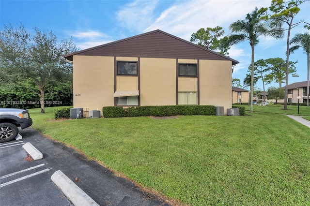 view of side of property featuring a lawn and cooling unit