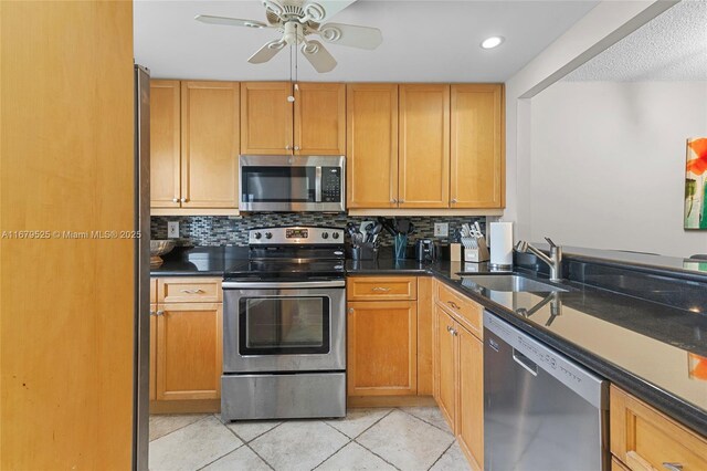 kitchen with tasteful backsplash, ceiling fan, appliances with stainless steel finishes, light tile patterned floors, and sink