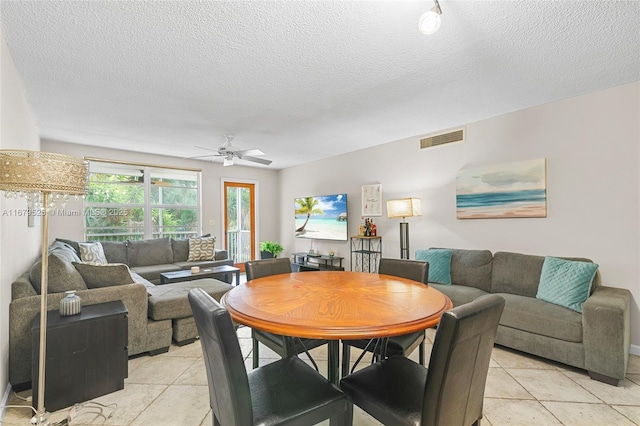 dining space featuring a textured ceiling, ceiling fan, and light tile patterned flooring