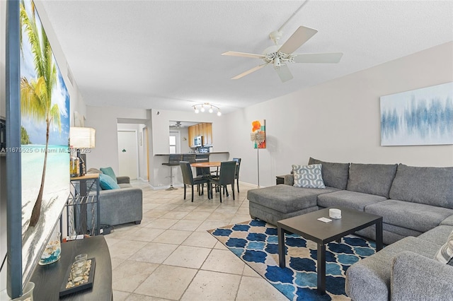 living room with ceiling fan, light tile patterned flooring, and a textured ceiling