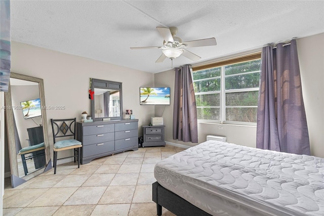 bedroom with ceiling fan, light tile patterned floors, and a textured ceiling