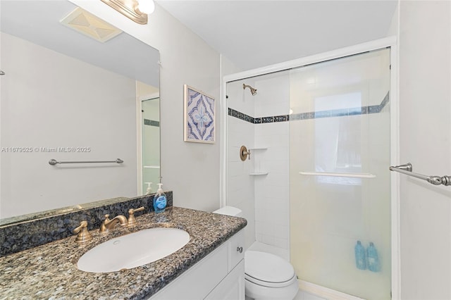 bathroom featuring toilet, a shower with door, and vanity