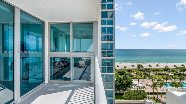 balcony with a water view and a view of the beach