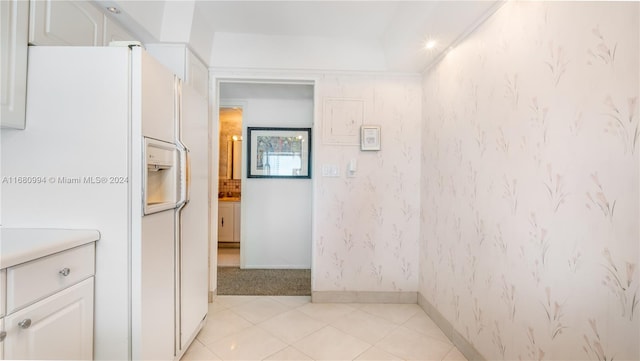 kitchen featuring white fridge with ice dispenser and white cabinetry