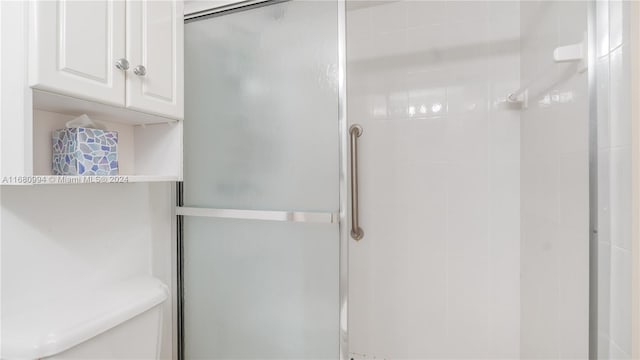 bathroom featuring a shower with door and toilet