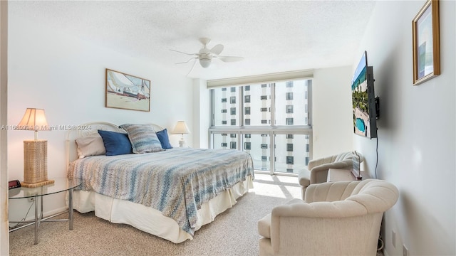 bedroom featuring ceiling fan, carpet flooring, a textured ceiling, and a wall of windows