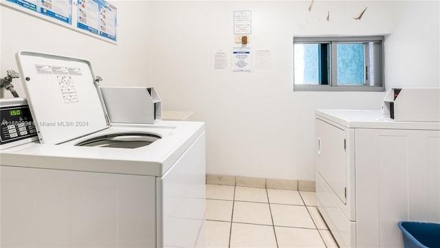 clothes washing area with washing machine and clothes dryer and light tile patterned floors