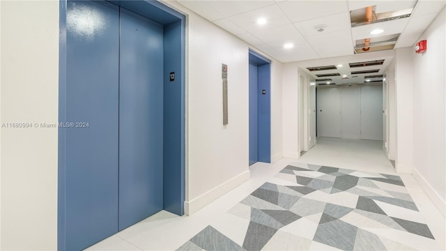 corridor featuring a paneled ceiling and elevator