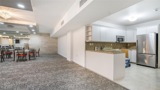 kitchen with kitchen peninsula, white cabinets, tasteful backsplash, blue cabinets, and stainless steel appliances