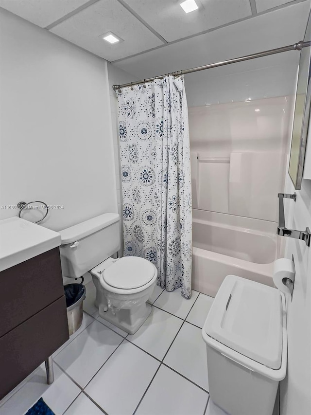 full bathroom featuring tile patterned floors, toilet, shower / bath combination with curtain, a drop ceiling, and vanity