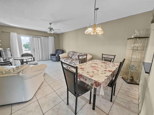 tiled dining space with ceiling fan with notable chandelier