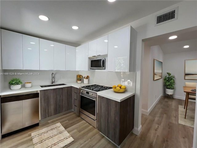 kitchen featuring white cabinets, sink, light wood-type flooring, appliances with stainless steel finishes, and dark brown cabinets