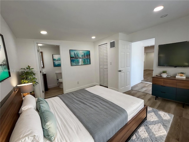 bedroom with a closet, wood-type flooring, and ensuite bath