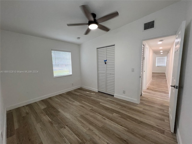 unfurnished bedroom featuring hardwood / wood-style flooring, ceiling fan, and a closet