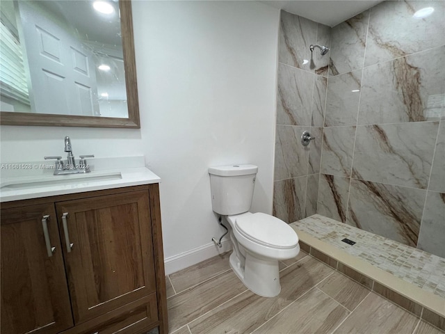 bathroom featuring vanity, toilet, and a tile shower