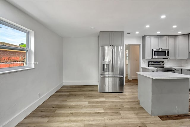 kitchen with tasteful backsplash, gray cabinets, light hardwood / wood-style floors, and appliances with stainless steel finishes