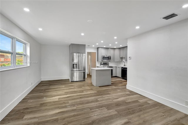 kitchen featuring gray cabinetry, sink, a center island, stainless steel appliances, and hardwood / wood-style flooring