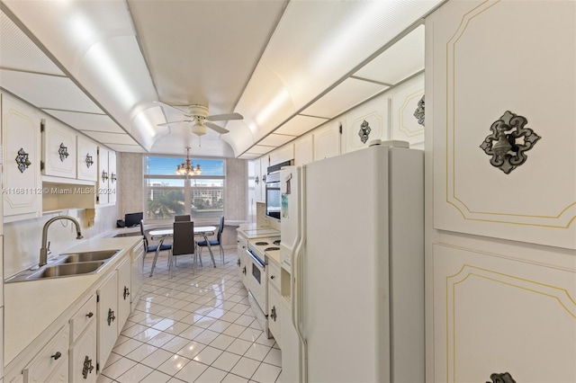 kitchen featuring white appliances, sink, light tile patterned flooring, white cabinets, and ceiling fan with notable chandelier