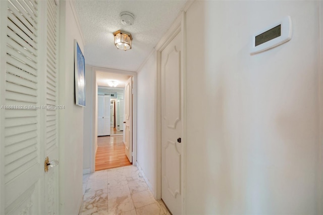 corridor with a textured ceiling and light wood-type flooring