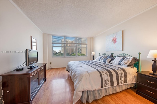 bedroom featuring light hardwood / wood-style flooring, multiple windows, and a textured ceiling