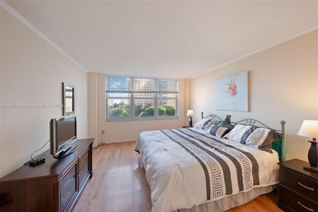 bedroom with ornamental molding, a textured ceiling, and light wood-type flooring