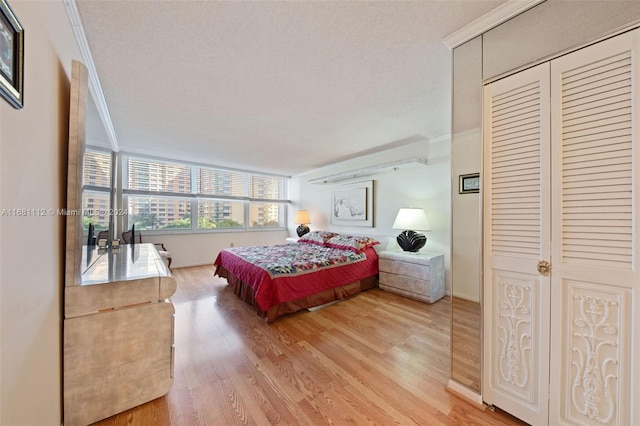 bedroom featuring wood-type flooring, a closet, ornamental molding, and a textured ceiling