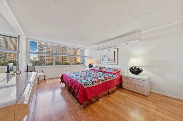 bedroom with ornamental molding, a textured ceiling, and light wood-type flooring