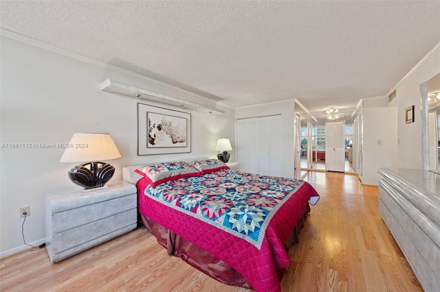 bedroom with a closet, a textured ceiling, ornamental molding, and light hardwood / wood-style flooring