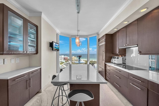 kitchen featuring ornamental molding, black electric cooktop, decorative light fixtures, a center island, and a breakfast bar area