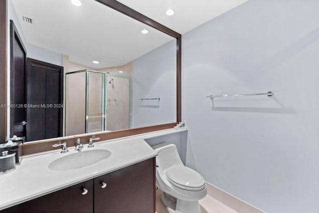 bathroom with vanity, a shower with shower door, and toilet