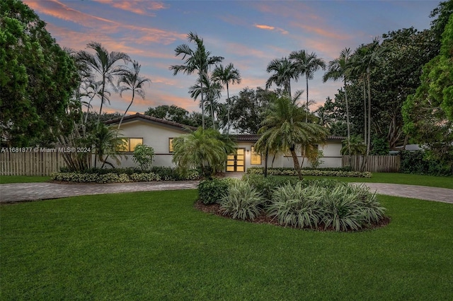 view of front of house with a lawn, stucco siding, and curved driveway