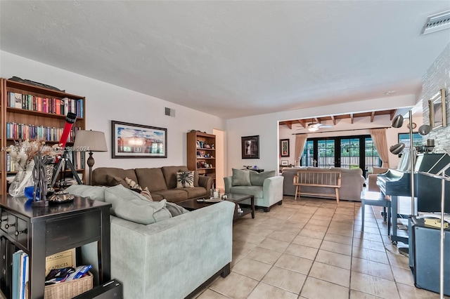 living room featuring visible vents, light tile patterned floors, and a ceiling fan