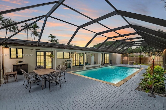 pool at dusk featuring grilling area, fence, a fenced in pool, a patio area, and french doors
