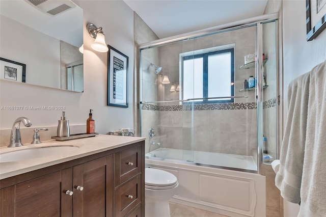 full bathroom featuring vanity, toilet, combined bath / shower with glass door, visible vents, and tile patterned flooring