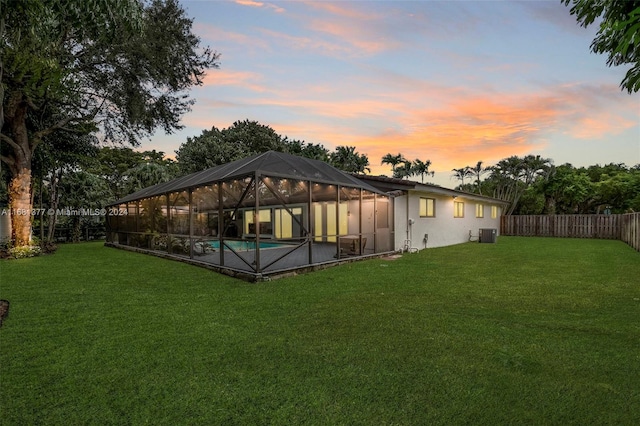 rear view of property with a fenced in pool, glass enclosure, a yard, central AC unit, and a fenced backyard