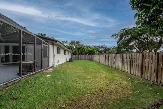 view of yard with central air condition unit, glass enclosure, and a fenced backyard