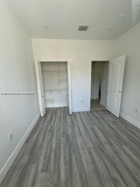 unfurnished bedroom with dark wood-type flooring, a closet, and a textured ceiling