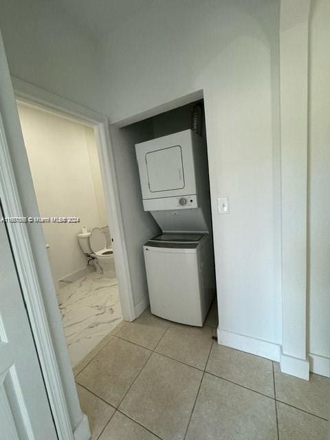 laundry area featuring light tile patterned flooring and stacked washer / dryer