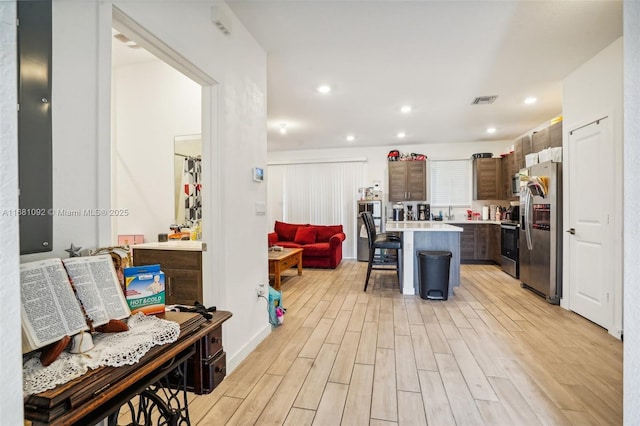 kitchen with a center island, a kitchen bar, appliances with stainless steel finishes, and light wood-type flooring