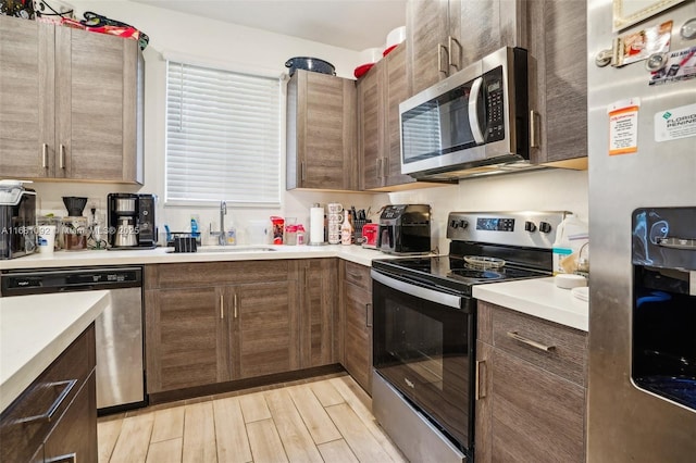 kitchen featuring light wood-type flooring, appliances with stainless steel finishes, and sink