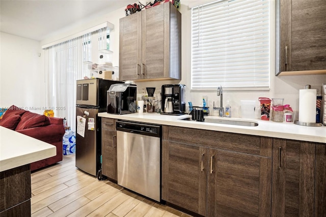 kitchen with dark brown cabinetry, light wood-type flooring, dishwasher, and sink