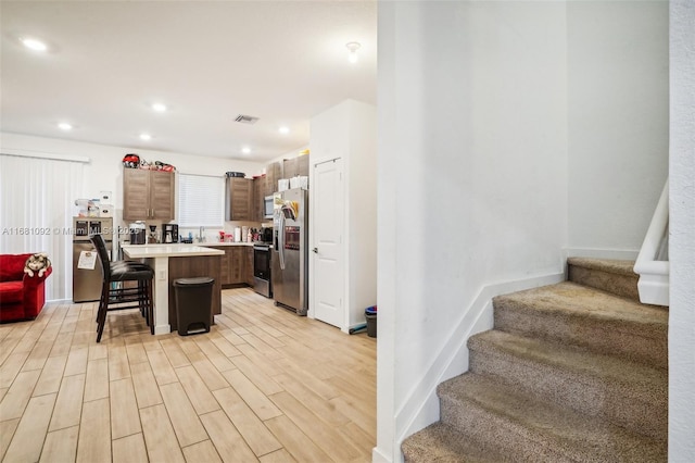 kitchen featuring a center island, a kitchen bar, stainless steel appliances, and light wood-type flooring