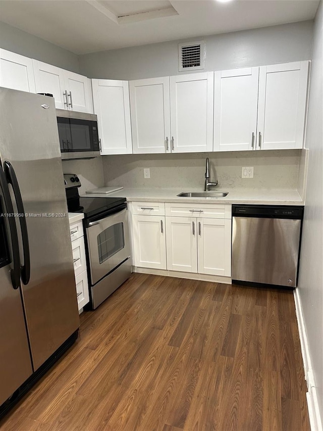 kitchen featuring stainless steel appliances, white cabinetry, dark hardwood / wood-style floors, and sink