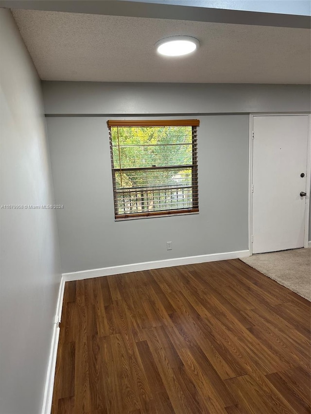 unfurnished room with a textured ceiling and dark hardwood / wood-style floors